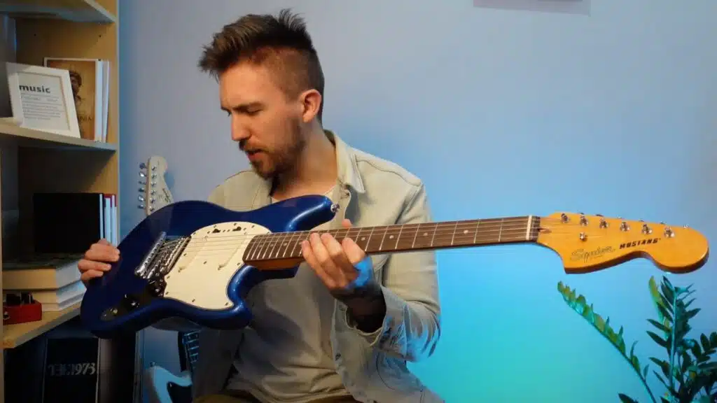 guitarist holding squier classic vibe 60s mustang